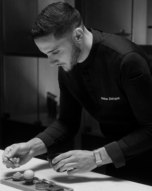 Black & White picture of the Jaeger-LeCoultre Made of Makers and Chocolate Chef Mathieu Davoine, wearing a Reverso Tribute Small Seconds Milanese Strap watch in Pink Gold, Q713216J