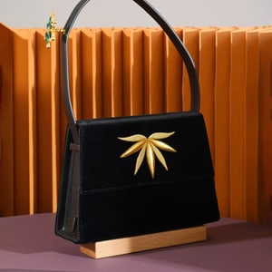 Jaeger-LeCoultre - Art Creation of a custom black handbag in front of a patterned orange wall for the Homo Faber Fellowship